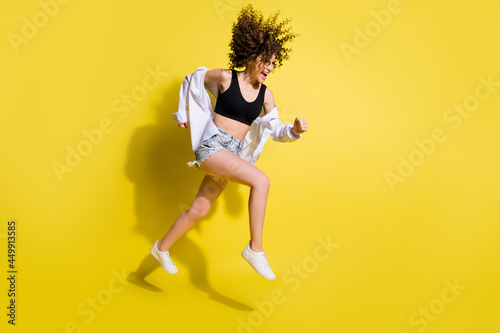 Full size profile photo of optimistic pretty girl run wear top shorts shirt sneakers isolated on yellow background
