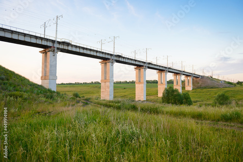 Modern railway bridge over the green ravine on a summer evening