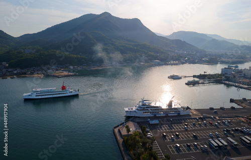 A bird's eye view of Tonosho port with sightseeing ferries navigating & parking in the harbor and sunlight reflected in the water on a beautiful summer morning in Shodoshima Island, Shikoku, Japan photo