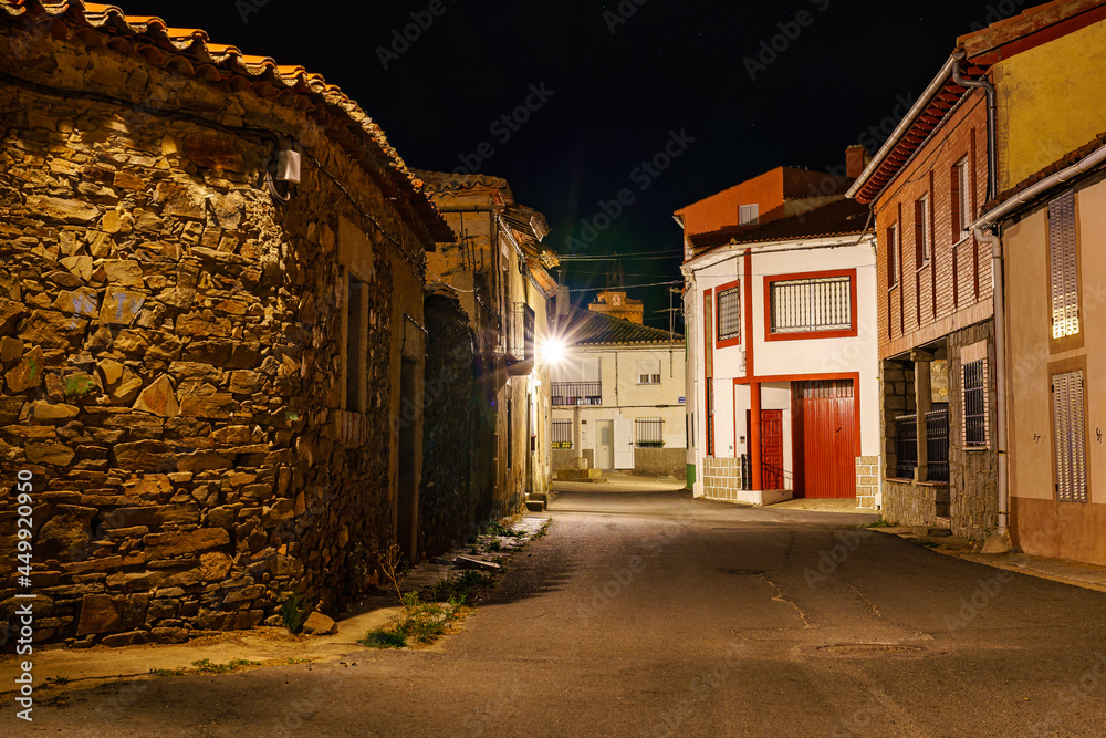 Spanish village street at night with old stone houses.