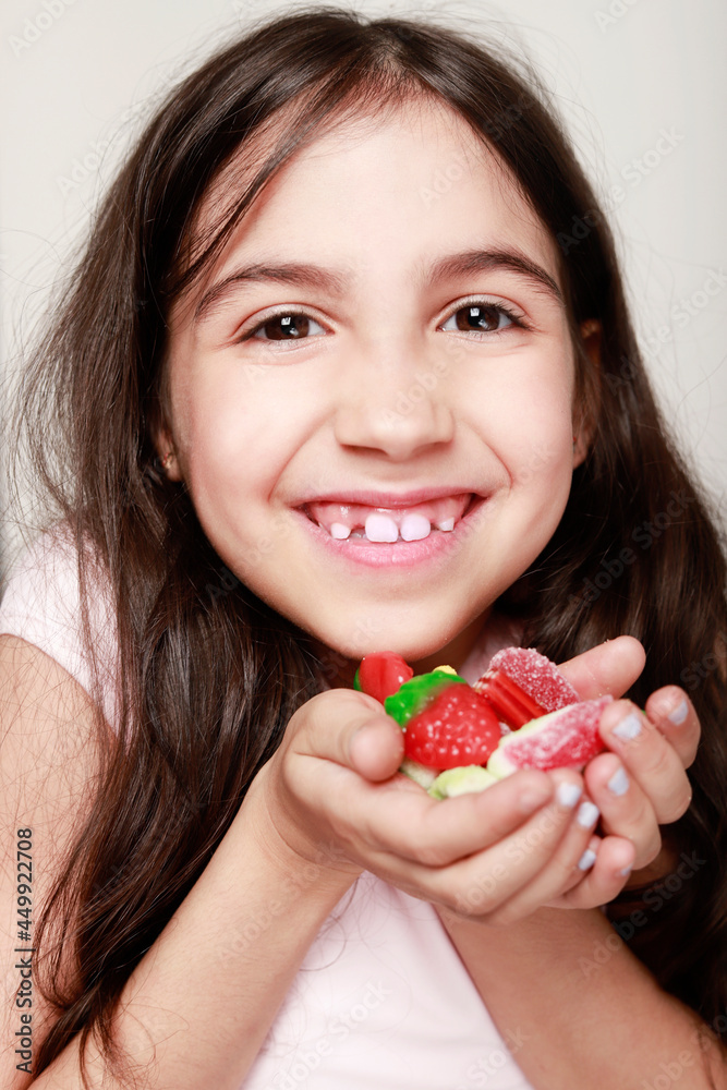 girl smiling at camera with lots of candies in her hands girl smiling at camera with lots of candies in her hands
