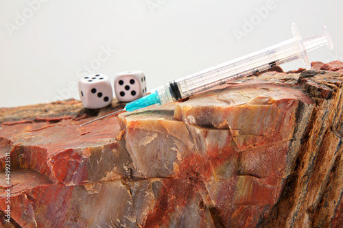 Get vaccinated and do not play games with your health.  Needle, dice, and rock in conceptual image reflecting decision based on hard facts and science. photo