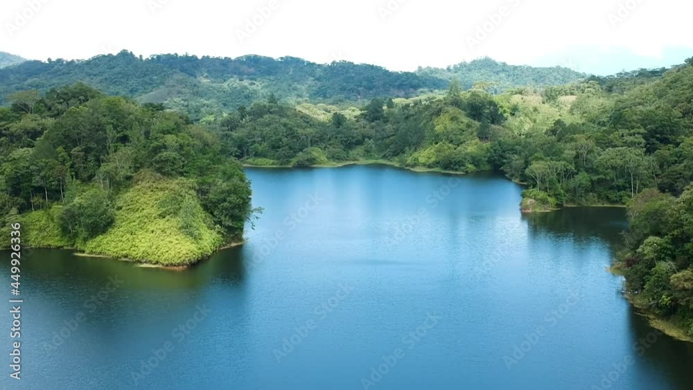 aerial view of water reservoir surrounded by a green forest in a sunny day aerial view of water reservoir surrounded by a green forest in a sunny day