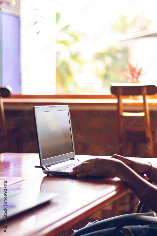 Close-up side view of female fingers typing on laptop keyboard in the meeting room