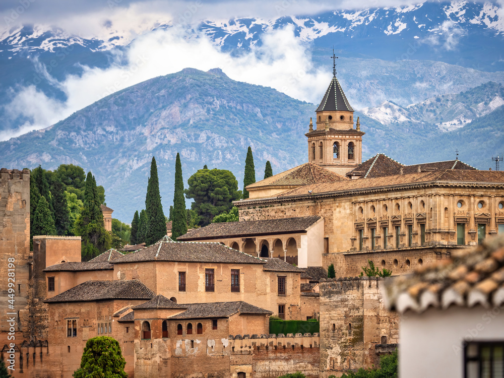 Granada, Spain - June 5, 2021: La Alhambra. The shot was taken from the city center with a telephoto lens. Some buildings of the fortress can be seen with the Sierra Nevada mountains in the background