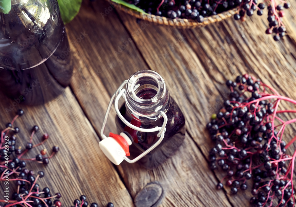 A bottle of black elder syrup with fresh elderberries - alternative medicine A bottle of black elder syrup with fresh elderberries - alternative medicine