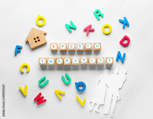 Cubes with text SPEECH THERAPIST, letters and figure of family on white background photo