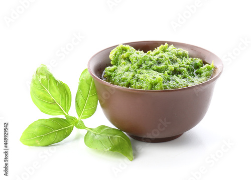 Bowl with fresh pesto sauce and basil leaves on white background