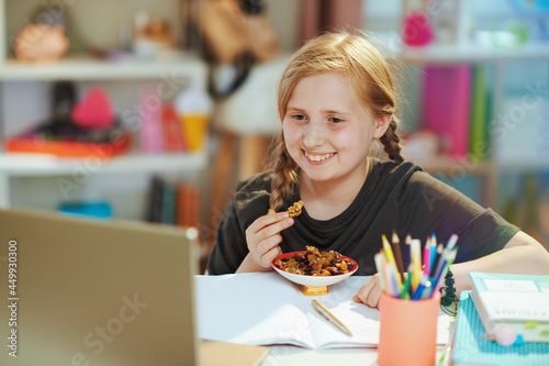 happy pupil having distance education and eating healthy snack