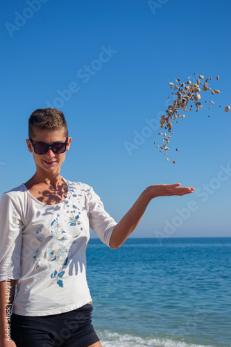 Beautiful woman throwing stones in the air at the beach.