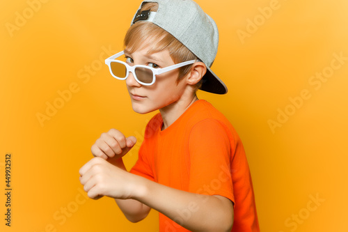 a child in glasses for watching movies clenched his fists and looks askance at the camera photo