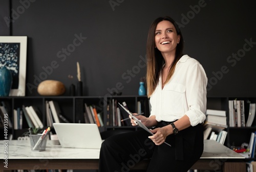 Confident stylish european middle aged woman standing at workplace, 30s lady executive leader manager looking at camera photo