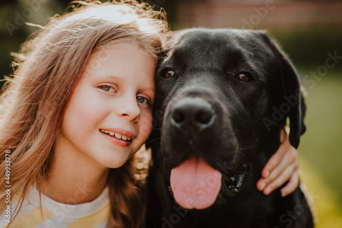Portrait of pretty young girl and black two years old labrador retriever