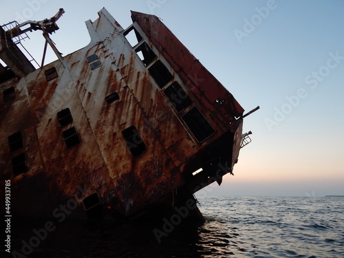 part of the sunken ship looks out of the water and is covered with rust