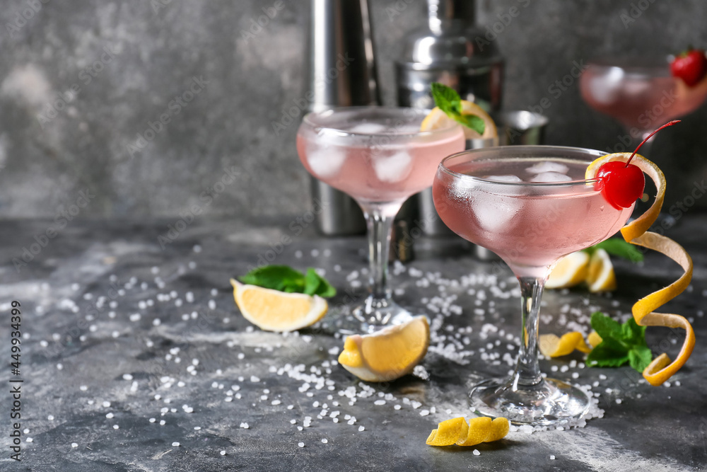 Glasses of tasty cosmopolitan cocktail, slices of lemon, mint and sea salt on dark background