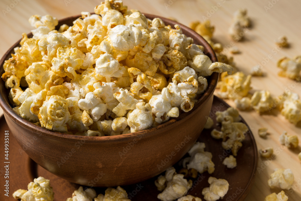 Caramel popcorn in a brown clay bowl on a wooden table top. Caramel popcorn in a brown clay bowl on a wooden table top.
