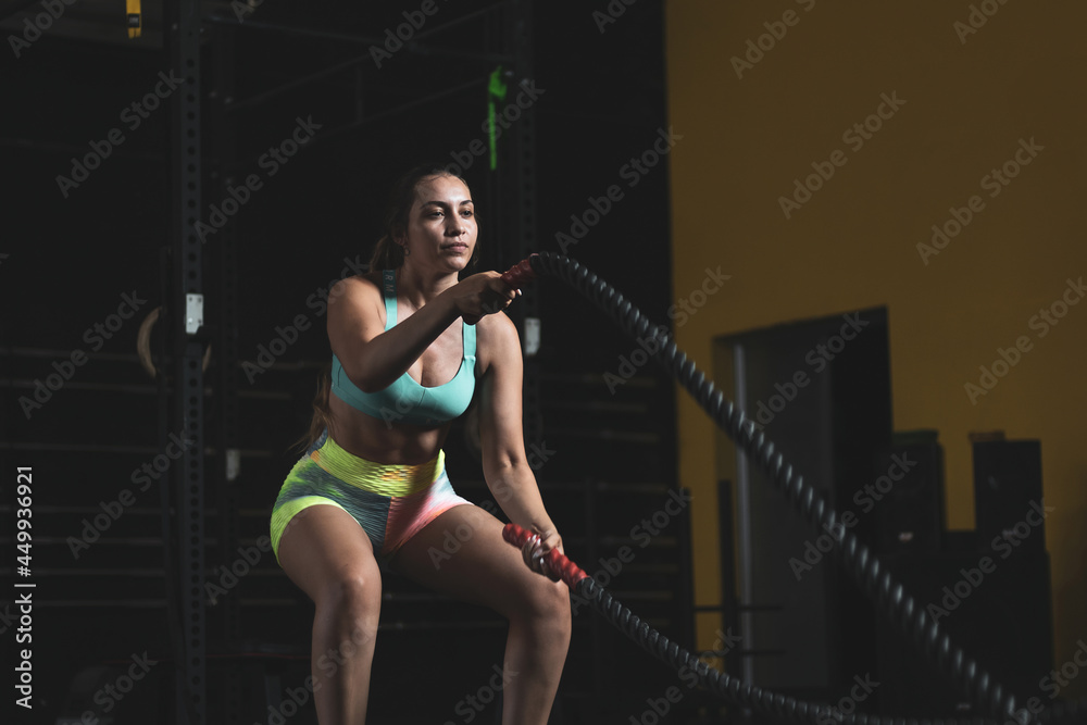 a Colombian girl moving some ropes inside a gym.