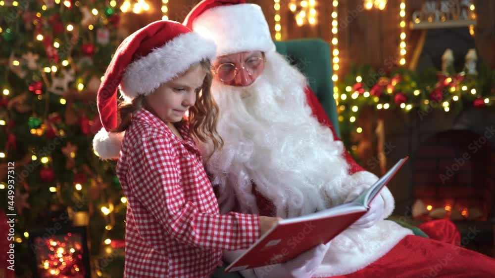 Little girl in pajama and Santa reading magic book