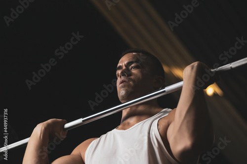 a Turkish man doing a shoulder exercise in a gym.