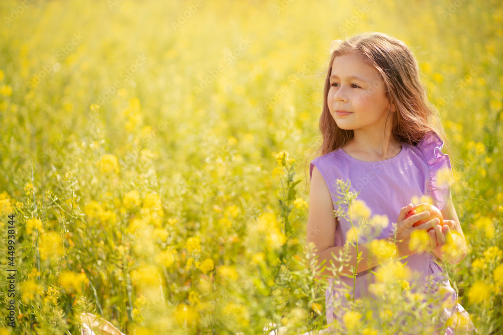 Cute little girl with a apple in a blooming canola field. Cute little girl with a apple in a blooming canola field.