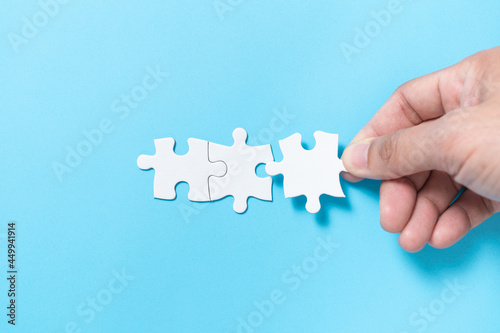 Hand push a piece of jigsaw puzzle to complete the mission for business merging concept or coorperate acquisition photo