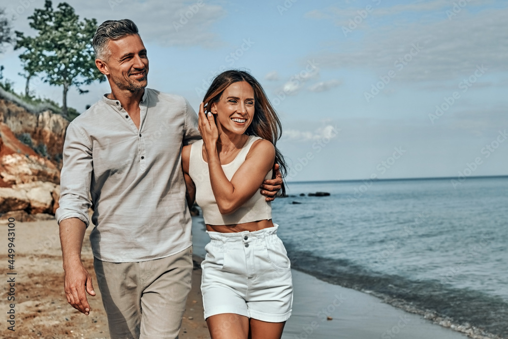 Happy attractive couple walking on beautiful sunny beach.