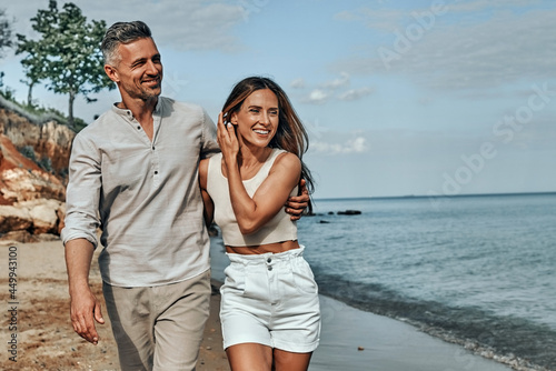 Happy attractive couple walking on beautiful sunny beach.