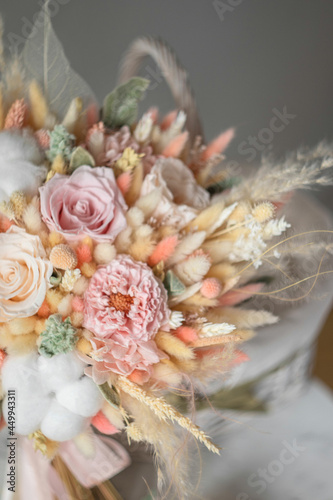 Stylish bridal bouquet of preserved flowers and lagurus with boutonniere. Dried and preserved flowers brides bouquet in delicate peach tones from cotton, roses and lagurus.