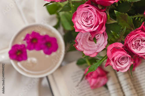 Beautiful pink roses with opened blured book and coffee cup in the background