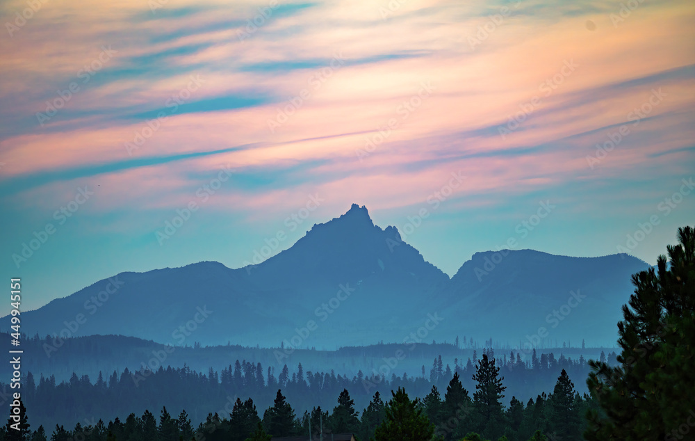 Sunset and silhouette of Three fingered jack mountain and layered hills with forest fire smoke near Black Butte Ranck, Sisters Oregon