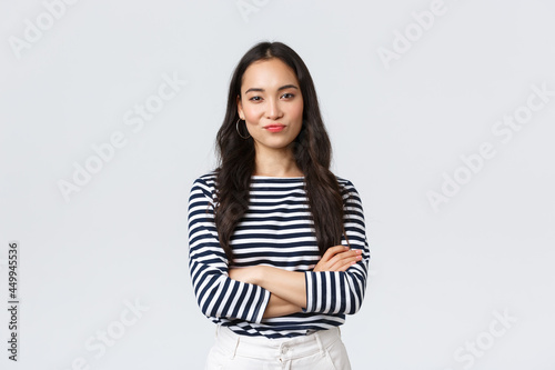 Lifestyle, beauty and fashion, people emotions concept. Skeptical and judgemental asian female office manager looking picky, smirk and pouting dissatisfied, cross arms chest photo