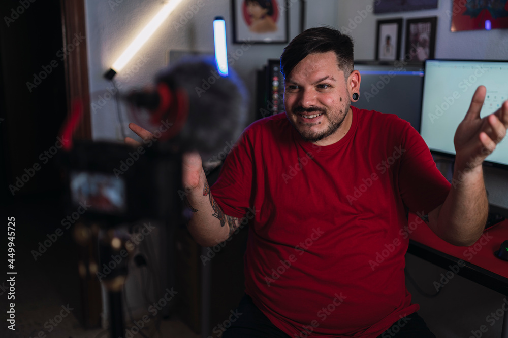 Chico joven gordo con camiseta roja grabando frente a una cámara en un set up gamer Chico joven gordo con camiseta roja grabando frente a una cámara en un set up gamer