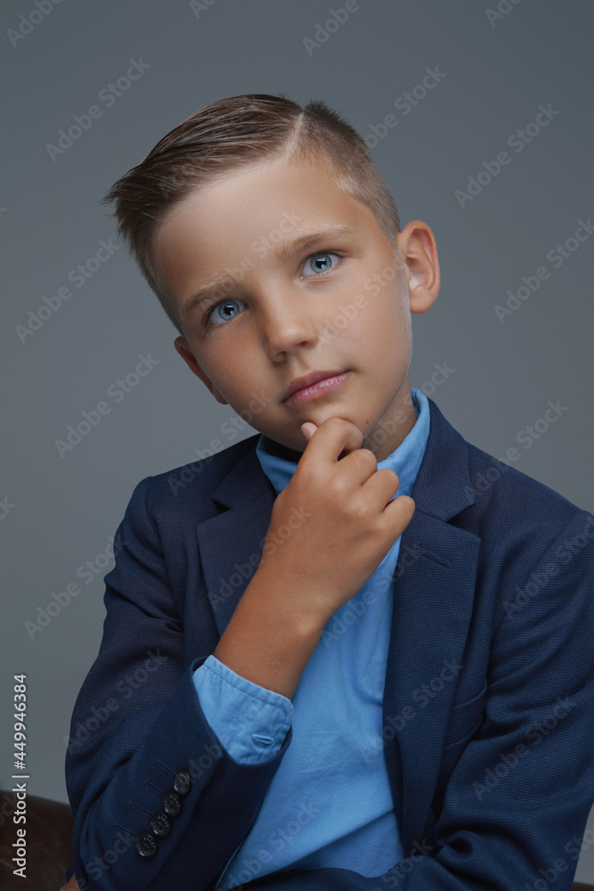 Pensive preteen boy dressed in suit against gray background Pensive preteen boy dressed in suit against gray background