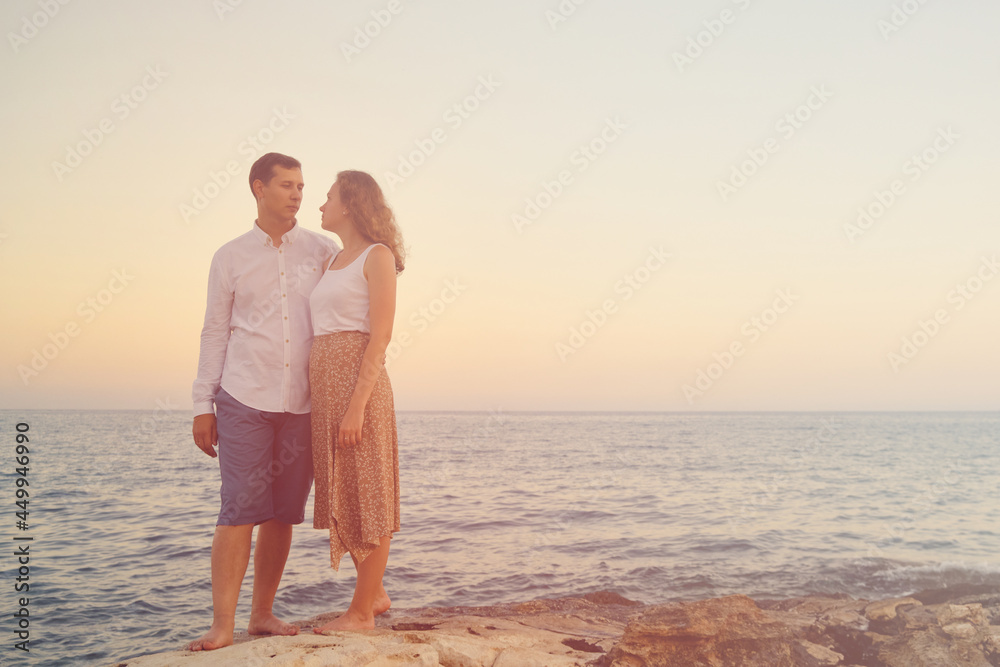 Young adult heterosexual couple at romantic date. Young man and woman cuddling and look to each other. Seaside romantic walk