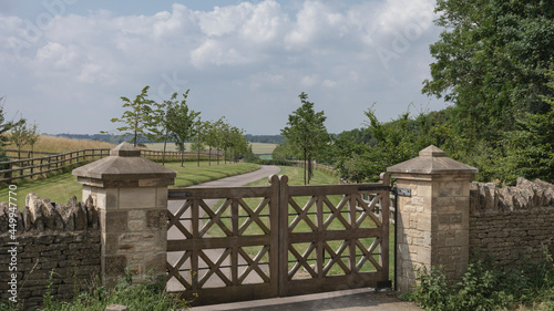 Looking down a driveway through ornate wooden gates