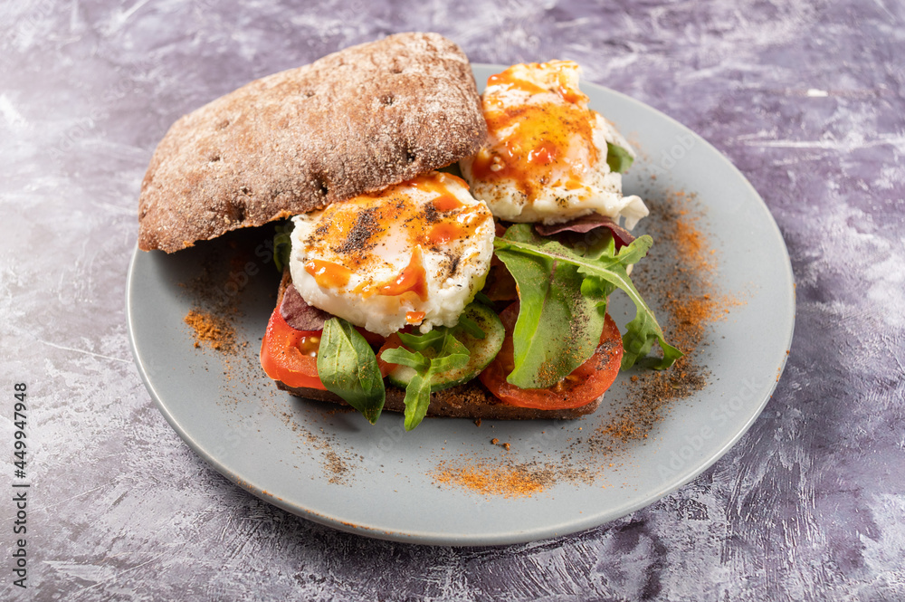 Poached egg sandwich. The eggs are sprinkled with a variety of spices. Sandwich on a plate. Poached egg sandwich. The eggs are sprinkled with a variety of spices. Sandwich on a plate.