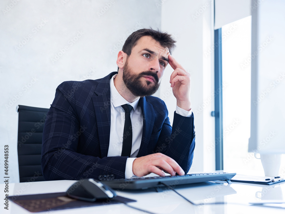 Concentrated business man in suit looking at monitor, typing and thinking in office. Concentrated business man in suit looking at monitor, typing and thinking in office.