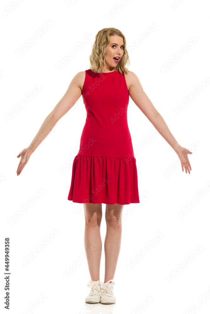 Young Woman In Red Mini Dress And Sneakers Is Standng With Arms Outstretched Young Woman In Red Mini Dress And Sneakers Is Standng With Arms Outstretched
