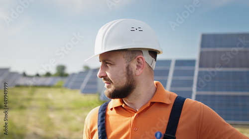 Portrait of male engineer in hard helmet turning head and looking to camera. Positive worker. Ecological industry. Solar farm concept. Concept for renewable energy, technology, future. © GRAFStock