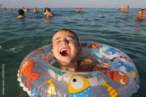 Swiming happy boy, child with life-saving inflatable circle in Protaras, Cyprus. Vrisy Bay Beach. Summer swim. Bathing kid in water. Active sea recreation. Summer swim, travel. Bathing child in water photo