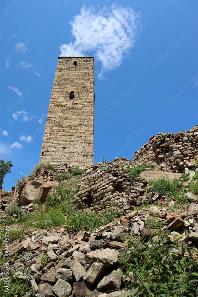 tall stone battle tower of old Kahib - abandoned ancient village in Dagestan caucasus mountains with blue summer sky background