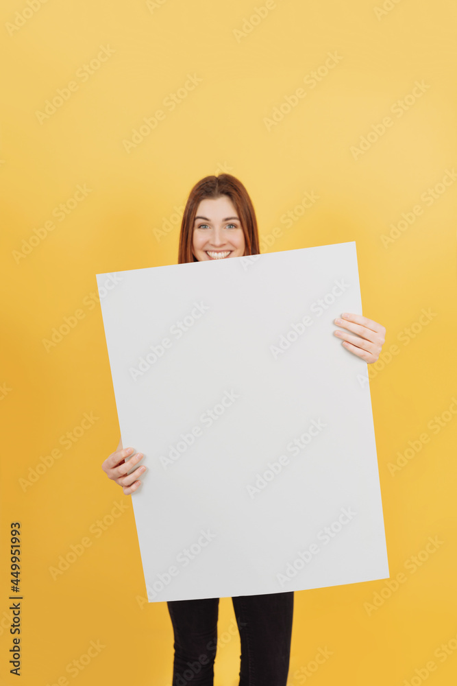 Vivacious young woman holding up a white blank board Vivacious young woman holding up a white blank board