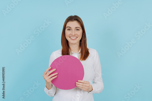 Happy smiling young woman holding a blank pink circular card