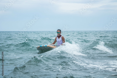 Skilled male Hispanic paddleboarder sitting on his paddleboard at sea photo