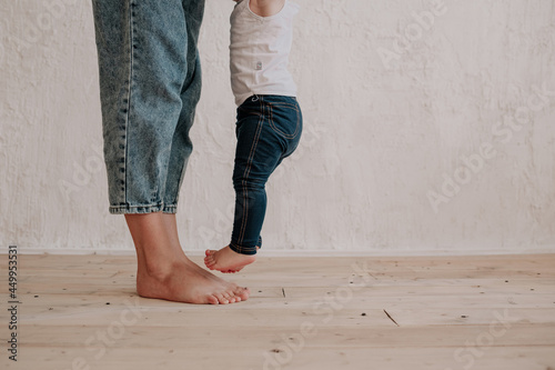 close-up of mom's legs and little daughter on a wooden floor