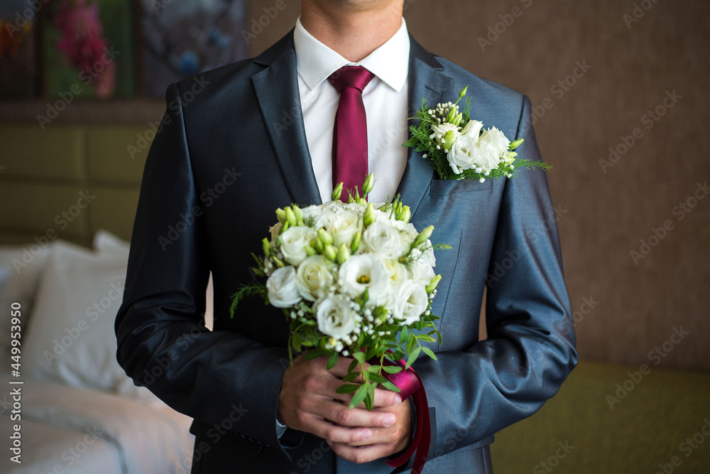 man holds a wedding bouquet in his hands.The Concept Of Valentine's Day.Wedding concept.the groom with bouquet.The groom in the suit holds a wedding bouquet.bridal bouquet. man holds a wedding bouquet in his hands.The Concept Of Valentine's Day.Wedding concept.the groom with bouquet.The groom in the suit holds a wedding bouquet.bridal bouquet.