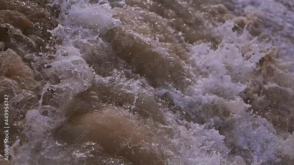 Close-up texture of the surface of a sea or ocean wave that comes to the sandy coast. Natural background with splashes of water and foam. Slow motion vacation summer concept Close-up texture of the surface of a sea or ocean wave that comes to the sandy coast. Natural background with splashes of water and foam. Slow motion vacation summer concept