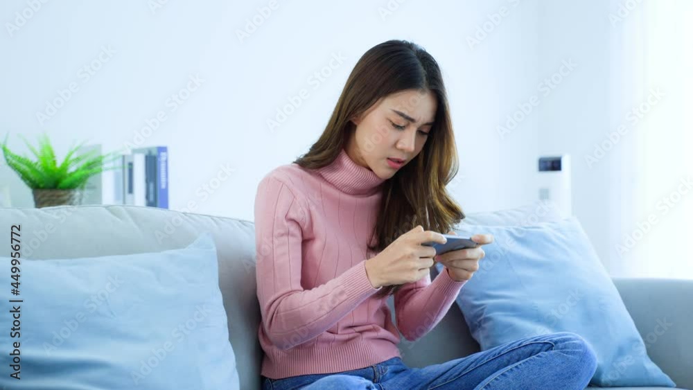 Asian frustrated beautiful woman play mobile game on cellphone at home Asian frustrated beautiful woman play mobile game on cellphone at home