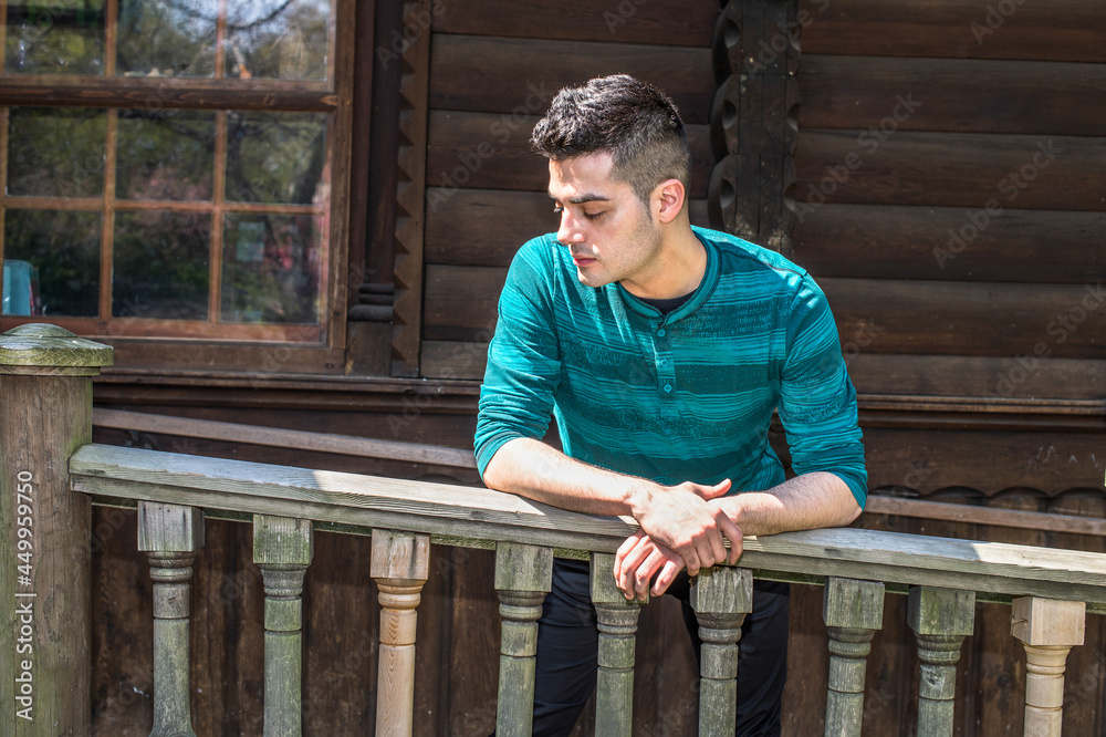 A young handsome guy is standing by wooden railing and into deeply thinking.. A young handsome guy is standing by wooden railing and into deeply thinking..