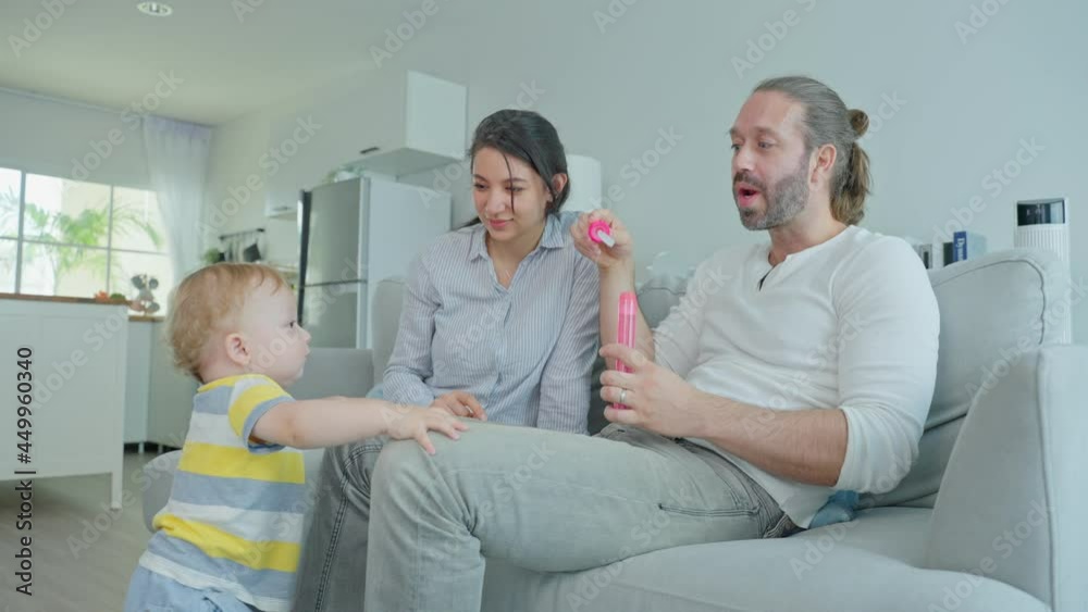 Caucasian happy loving parent play with baby toddler in living room.